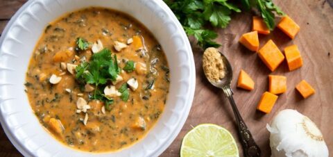 a bowl full of stew topped with herbs and peanuts.