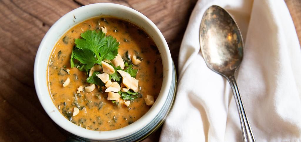 a bowl of stew with peanuts on top of it.