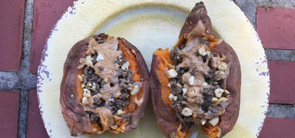 two sweet potatos cut in half filled with peanut sauce.