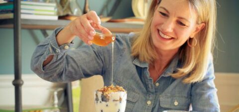 a woman dripping syrup in a cup filled with cream.