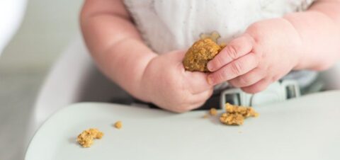 a baby holding a sweet dough in their hands.