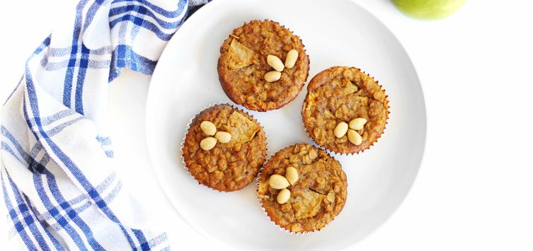 a white plate topped with four apple muffins.