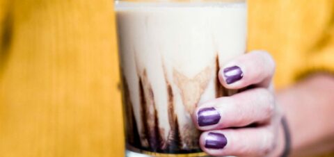 a woman holding a tall glass of milkshake.