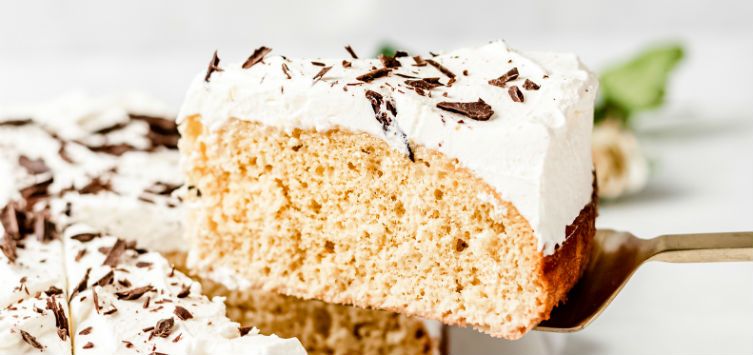 a slice of cake with white frosting and chocolate sprinkles.
