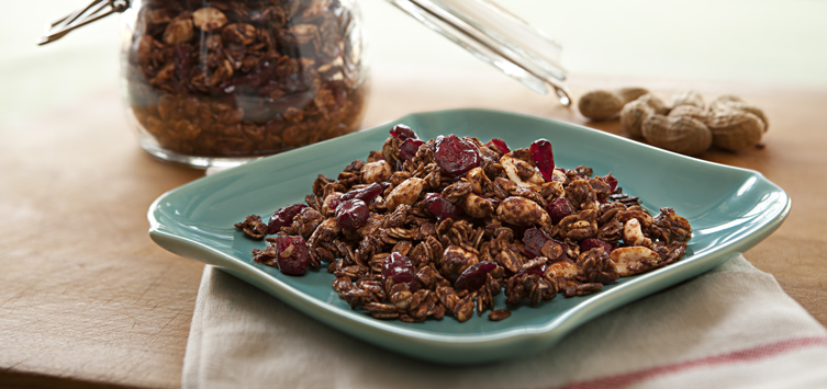 a blue plate topped with granola next to a jar of nuts.