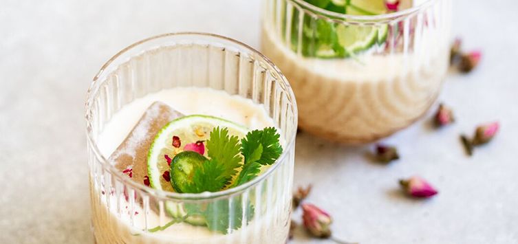 a cocktail glass topped with a lime slice and dried rose petals.